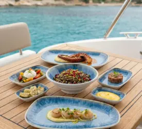 Ahşap tekne masasında ızgara ahtapot, deniz tarağı, burrata salatası, tartar ve gurme mezelerle sunulan açık mavi iris reaktif sir efektli kırılmaz melamin 7 parça Blue Iris (504407) kayık sunum seti.