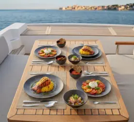 Ahşap tekne masasında ıstakoz, burrata salatası, meze ve sos ikramlarıyla sunulan koyu toprak tonlarında mat kil dokulu kırılmaz melamin 8 parça Velora Clay (M504108) 2 kişilik yemek takımı seti.