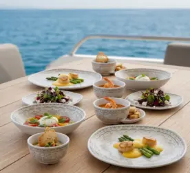 Ahşap tekne masasında deniz tarağı, burrata salatası, çorba, karides ve ikramlıklarla sunulan otantik altın-bronz eskitme desenli kare kırılmaz melamin 8 parça Old Ivory (M503208) 2 kişilik yemek takımı seti.