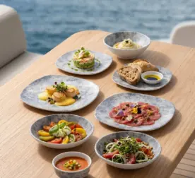 Ahşap tekne masasında deniz tarağı, carpaccio, burrata salatası, tartar ve ekmek ikramlarıyla sunulan açık gri-mavi bulut mermer dokulu kare kırılmaz melamin 8 parça Velora Cloud (M506208) 2 kişilik yemek takımı seti.
