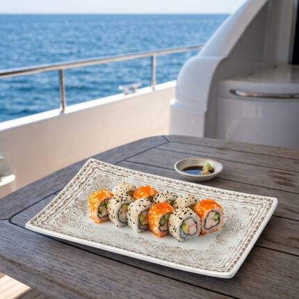 Ahşap tekne masasında soya sosu ve wasabi eşliğinde karışık sushi roll sunumuyla gösterilen krem zemin üzerine altın-bronz eskitme desenli büyük boy kırılmaz melamin Old Ivory 3'lü dikdörtgen servis ve sunum tabağı seti (30 x 20,7 cm).