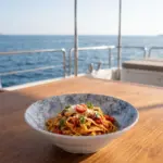 Ahşap tekne masasında domates soslu ve fesleğenli tagliatelle makarna sunumuyla gösterilen açık gri-mavi bulut mermer dokulu kırılmaz melamin Velora Cloud 3'lü derin makarna ve salata kasesi seti (Ø 23,6 cm).