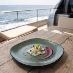 Ahşap tekne masasında mor pancar püresi ve taze mikro filizler eşliğinde beyaz balık ceviche sunumuyla gösterilen yeşil mineral reaktif taş efektli kare/yuvarlak yumuşak hatlı kırılmaz melamin Green Minerra 3'lü servis ve yemek tabağı seti (22 x 22 cm).